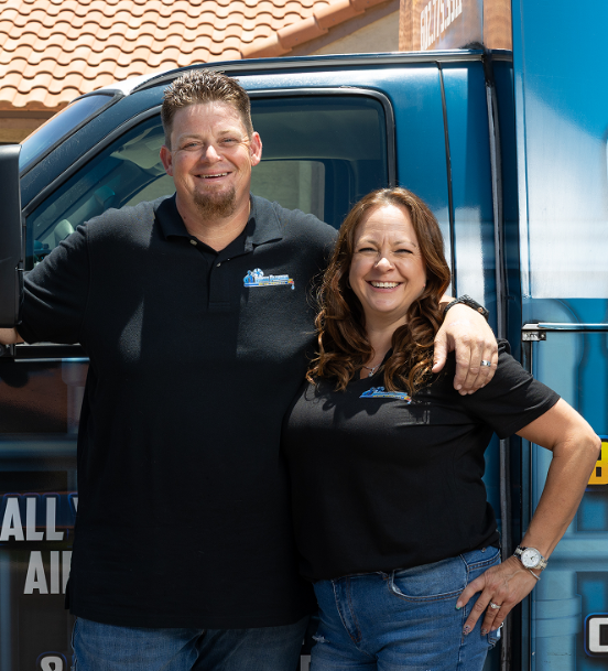 About Us 30 Robert and Amy Bridge smiling by Bridge Plumbing & HVAC service van.