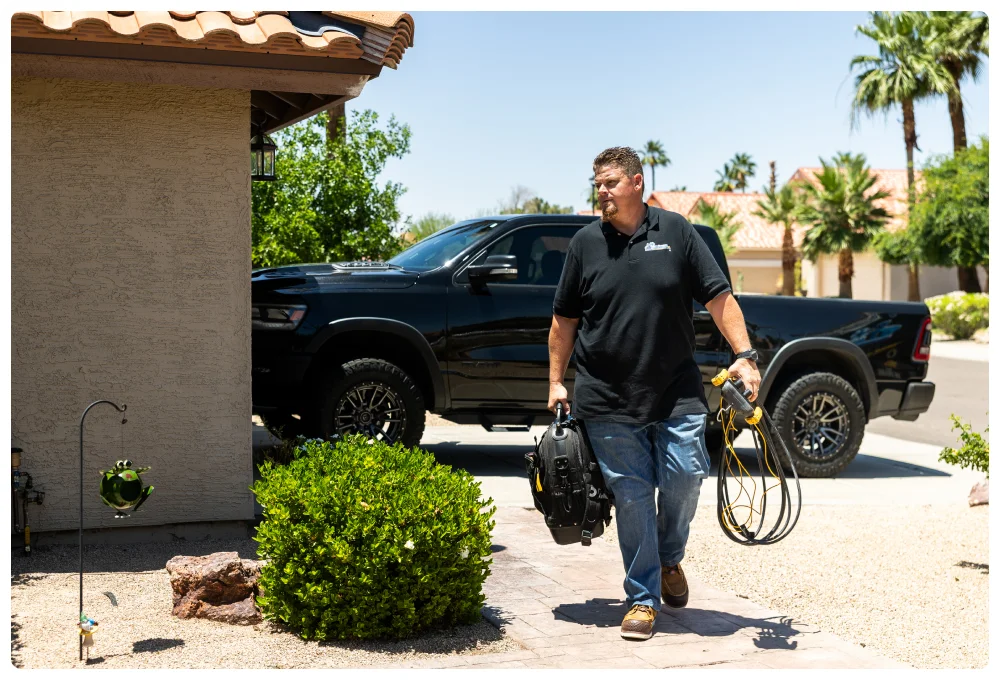 Commercial 37 Robert Bridge carrying tools and cables while walking toward a customer’s home.