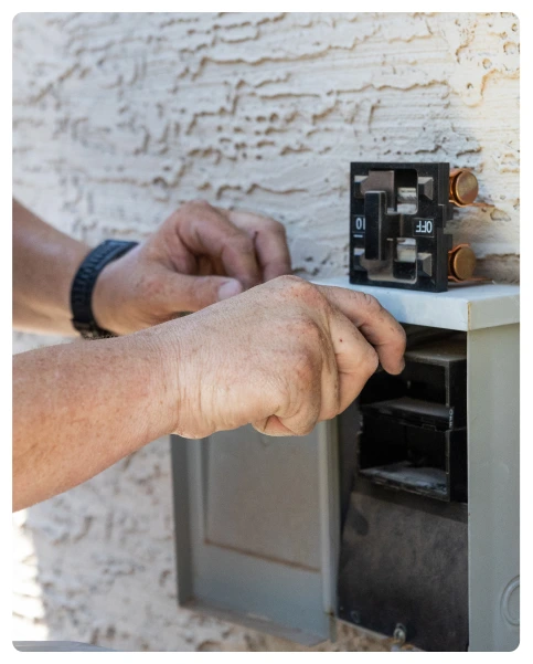 Residential 37 Technician working on an outdoor electrical breaker panel with screwdriver.