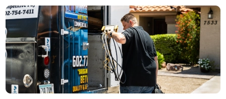 Technician unloading tools from Bridge Plumbing & HVAC service van at customer home.