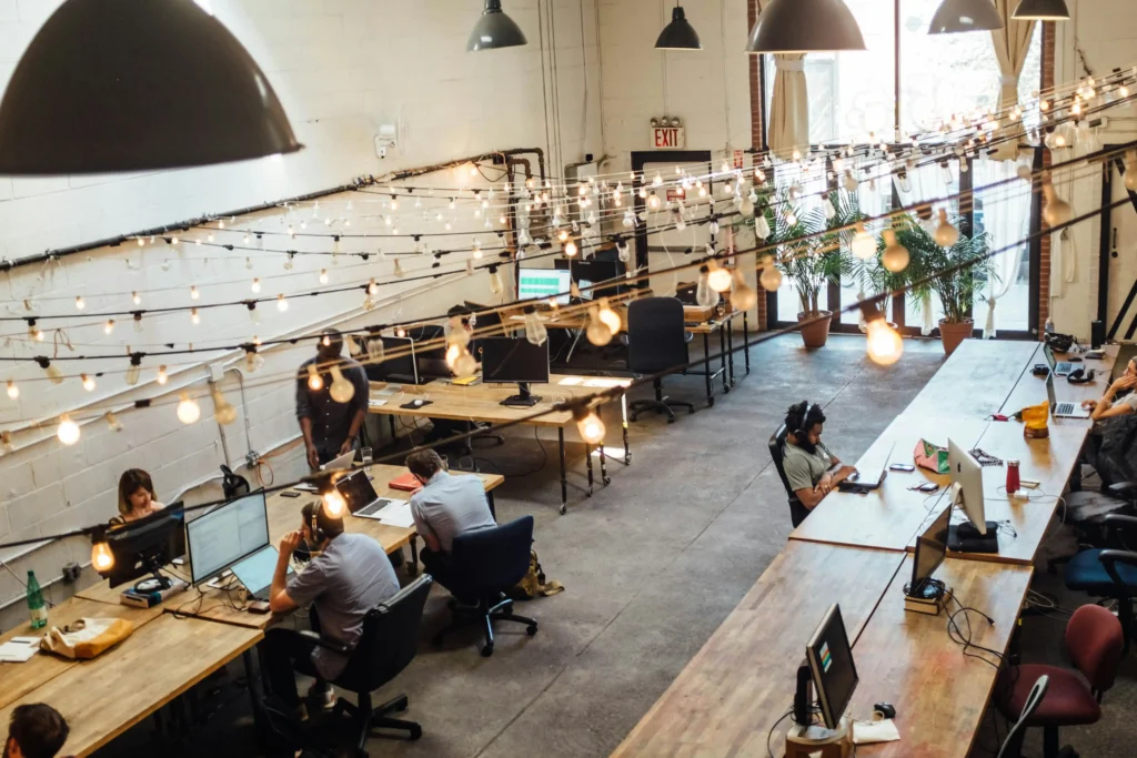 Open-plan office with long desks, string lights, and people working on computers. HVAC Repair or Replacement