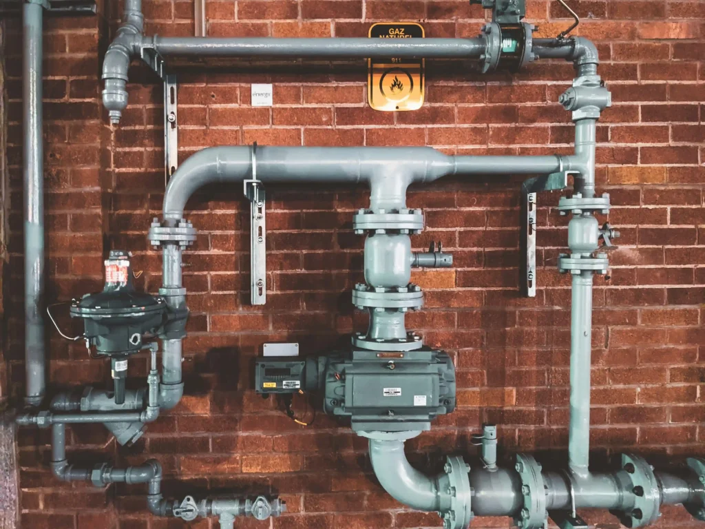 Water Heater Trouble? 5 Warning Signs You Shouldn’t Ignore 1 Industrial plumbing pipes and valves mounted on a red brick wall. Water Heater Trouble