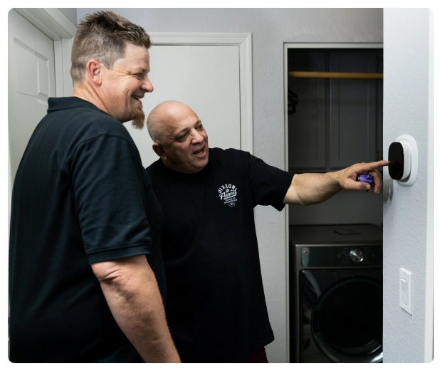 Career 33 Robert Bridge with man adjusting a digital thermostat on a wall.
