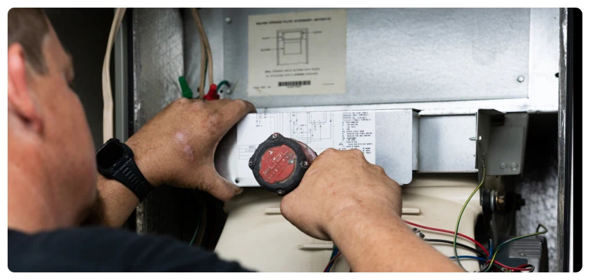 AC Repair 33 Technician adjusting wiring inside an HVAC unit with tools.